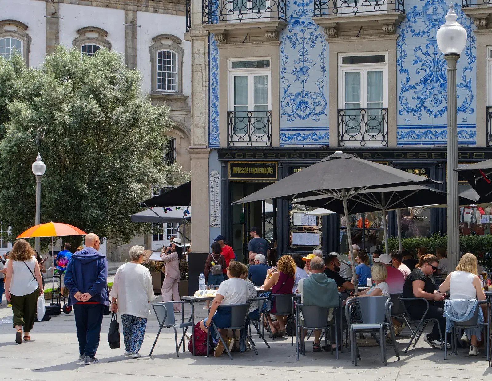 Friends at an outdoor café beneath tiled façades in historic Porto.