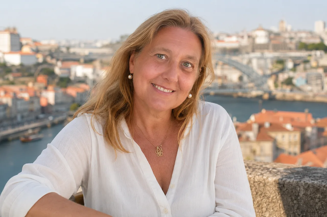 Portrait of Isadora Proença smiling outdoors in Porto, with the Dom Luís I Bridge softly blurred behind her.